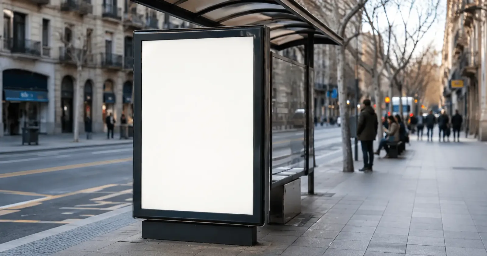 Marquesina publicitaria iluminada en una parada de autobús de una calle española con cartel genérico